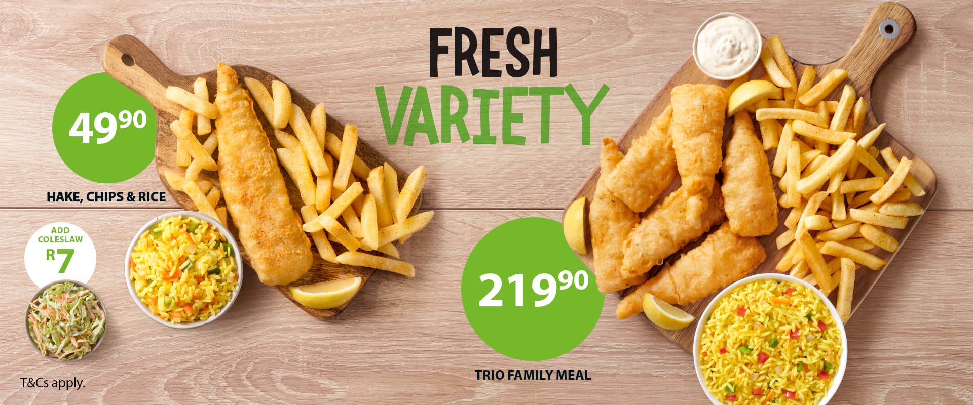 Takeaway lunch meals from Fishaways including seafood lunch box filled with hake fillets, fish pops, hake strips, onion rings, chips and Coke No Sugar against a wooden background.